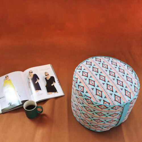 Pouf tondo con stampa geometrica azzurra nera e rosa, più rivista e tazza