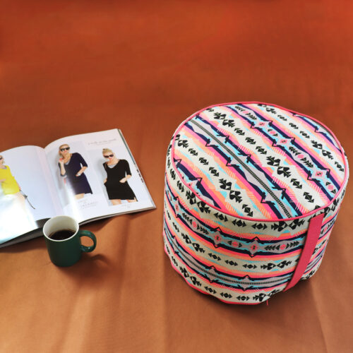 Pouf tondo con stampa geometrica fucsia, rivista e tazza